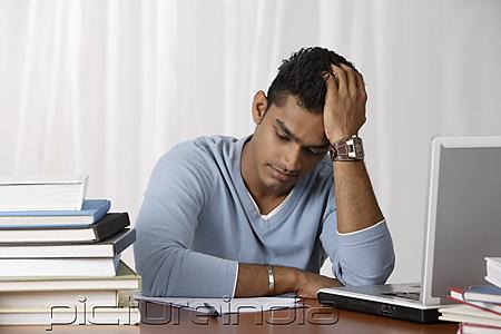 PictureIndia - young man studying at his desk, stressed