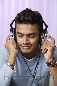 PictureIndia - young man with headphones on, listening to music intently