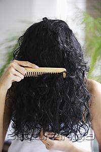 PictureIndia - Indian woman combing her hair with face covered.
