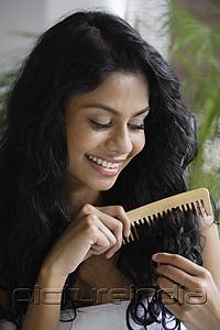PictureIndia - Indian woman smiling and combing her hair.