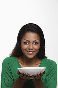 PictureIndia - Young woman holding white bowl and smiling