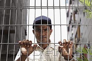 PictureIndia - Security guard holding fence and looking stern