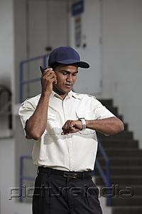 PictureIndia - Security guard looking at watch and talking on phone