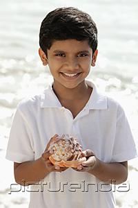 PictureIndia - Young boy holding sea shell and smiling