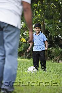 PictureIndia - Young boy kicking ball to his father
