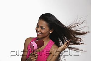 PictureIndia - woman blow drying her long hair and smiling