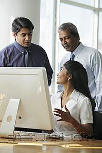 PictureIndia - Indian business people talking to each other around a computer
