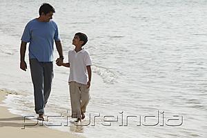 PictureIndia - Father and son holding hands and walking on beach