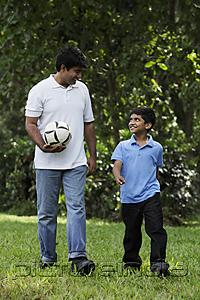 PictureIndia - Father and son walking together in park holding ball