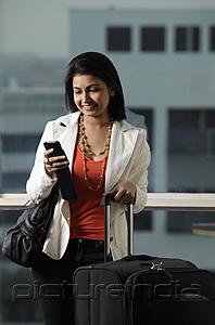 PictureIndia - woman holding suitcase and looking at text message