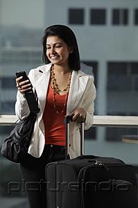 PictureIndia - woman holding suitcase looking at phone and smiling