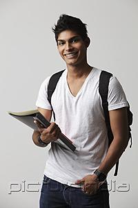 PictureIndia - young man holding books and wearing backpack.