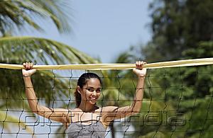 PictureIndia - Young woman holding volleyball net at the beach