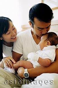 Asia Images Group - Father and mother holding baby girl, father kissing