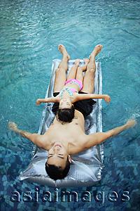 Asia Images Group - Father and daughter on inflatable bed in swimming pool