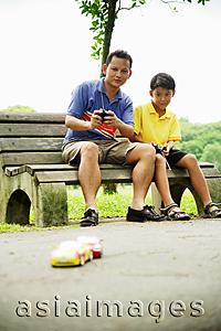 Asia Images Group - Father and son playing with remote control cars in the park
