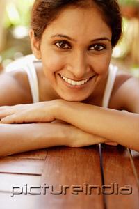 PictureIndia - Woman resting head on arms, smiling at camera