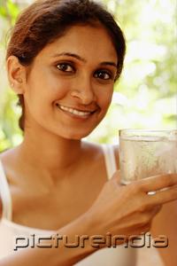 PictureIndia - Woman smiling at camera, holding glass of water