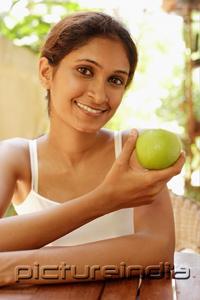 PictureIndia - Woman holding apple, smiling
