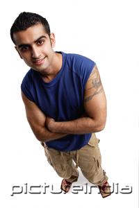 PictureIndia - Young man looking up at camera, arms crossed