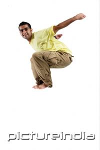 PictureIndia - Young man jumping in mid-air, arms outstretched