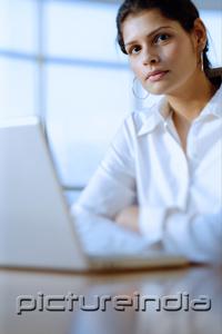 PictureIndia - Female executive in front of laptop, looking at camera