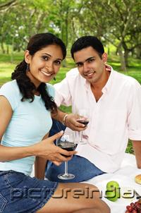PictureIndia - Couple holding wine glasses, looking at camera, portrait