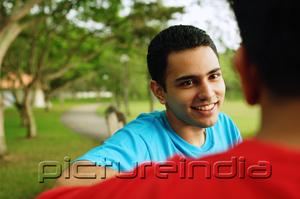 PictureIndia - Man smiling, facing another person, over the shoulder view