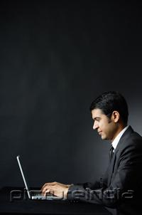 PictureIndia - Businessman using laptop, portrait