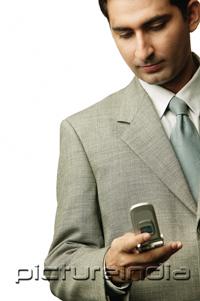 PictureIndia - Businessman holding mobile phone, looking down