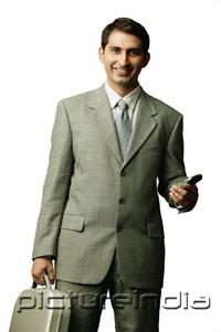 PictureIndia - Businessman holding mobile phone and briefcase, looking at camera