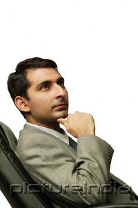 PictureIndia - Businessman sitting on chair, hand on chin, away