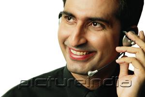 PictureIndia - Executive using headset, smiling, looking away
