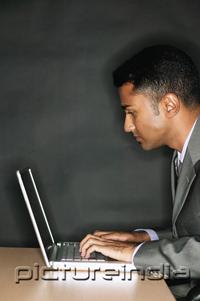PictureIndia - Businessman using laptop, side view