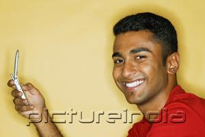 PictureIndia - Man holding mobile phone, smiling at camera