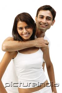 PictureIndia - Man hugging woman from behind, both looking at camera