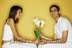 PictureIndia - Couple sitting face to face, woman holding flowers, man looking at camera
