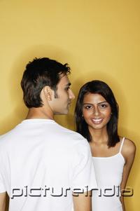 PictureIndia - Woman smiling facing camera, man in front of her, head turned in profile