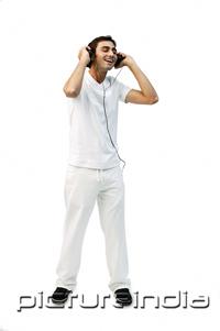 PictureIndia - Young man listening to headphones, eyes closed, smiling