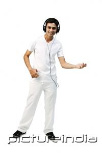 PictureIndia - Young man listening to headphones, playing air guitar