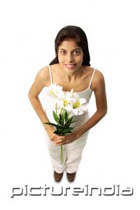 PictureIndia - Woman standing with flowers, looking at camera