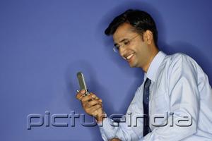 PictureIndia - Man using mobile phone, smiling