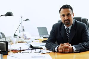 PictureIndia - Businessman at desk, looking at camera