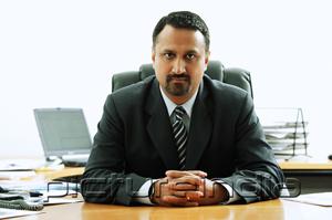 PictureIndia - Businessman at desk, looking at camera, hands clasped