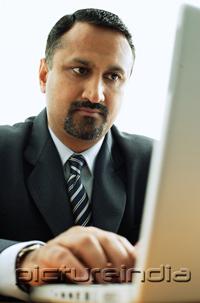 PictureIndia - Businessman at desk, using laptop