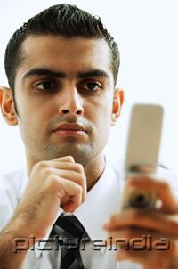 PictureIndia - Executive looking at mobile phone, hand on chin