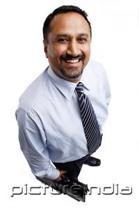 PictureIndia - Businessman standing, smiling at camera