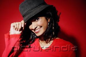 PictureIndia - Woman smiling at camera, pulling down hat on head
