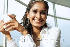 PictureIndia - Woman smiling at camera, holding mug