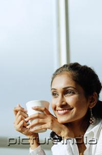 PictureIndia - Woman with mug in hand, smiling, looking away